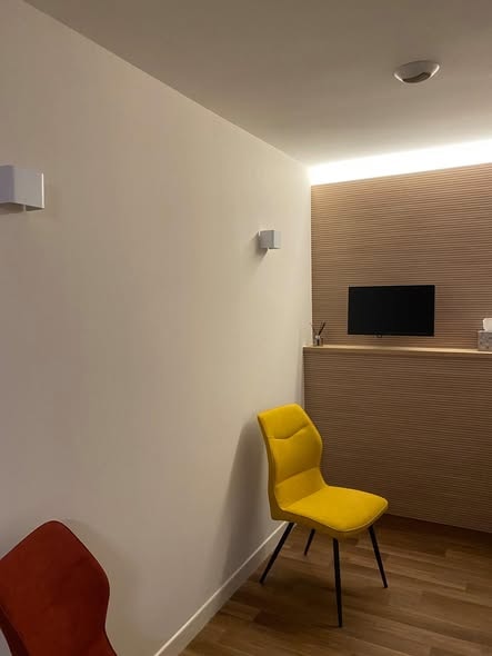 Cabinet d'attente avec lambris vertical bois clair en fond et TV intégrée
