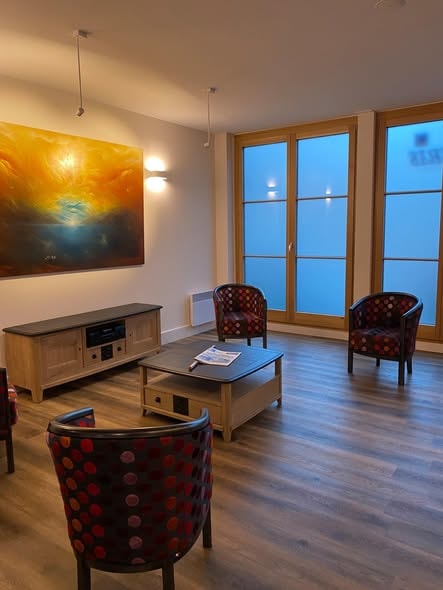 Lounge ERP avec fauteuils colorés, parquet et meuble TV chêne sur mesure